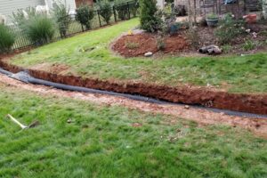 Top Gardens Landscaping installing a French drain system in a Charlotte yard.