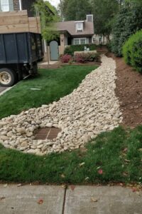 Top Gardens installing a French drain with a catch basin and dry rock creek bed in a Charlotte lawn.