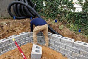 Top Gardens Landscaping installing a French drain and retaining wall in a Charlotte lawn.