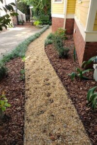 A curved pea gravel path with clean border edging running through freshly installed mulch beds, showing professional lawn care and top garden landscaping in Charlotte, NC.