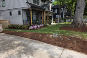 Top Gardens lawn mowing and mulch plant bed installation next to a concrete slab driveway in Charlotte, NC