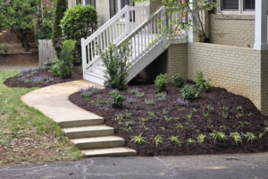 Fresh dark mulch applied to a sloped front yard garden bed next to concrete steps, a concrete slab walkway installed by Top Garden landscaping, Charlotte, NC.