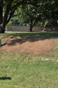 Lawn care and top garden landscaping in Charlotte, NC, featuring a freshly graded and leveled topsoil patch on a sloped backyard lawn.